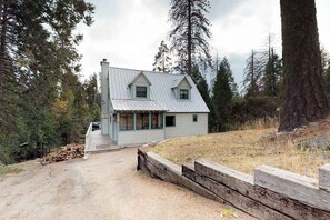 A rustic cabin with a sloped roof, a front porch, and a dirt driveway. - Foxtail Delight - West Village (Shaver Lake)