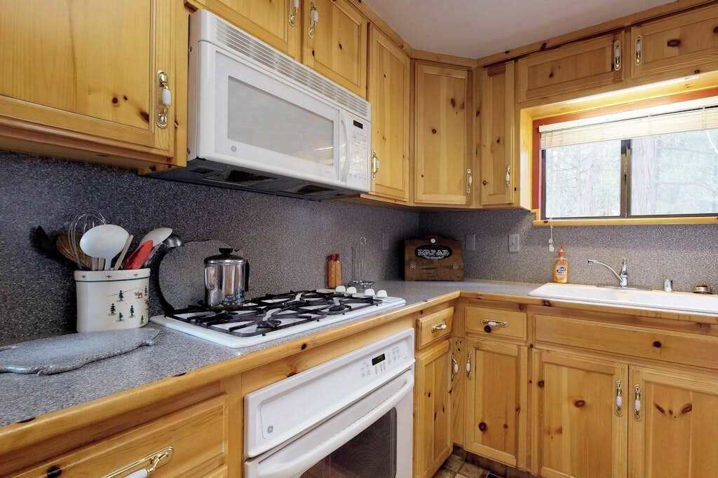 A kitchen with wooden cabinets, a microwave, a gas stove, and a sink.