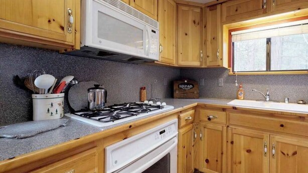 A kitchen with wooden cabinets, a microwave, a gas stove, and a sink. - Foxtail Delight - West Village (Shaver Lake)