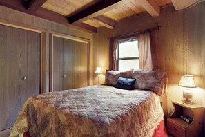Une chambre avec un grand lit, une table de chevet avec une lampe et une fenêtre avec des rideaux.
