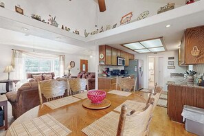 Ein geräumiges Wohnzimmer mit Essbereich, Holzmöbeln und einer Küche im Hintergrund.