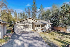 Ein eingeschossiges Haus mit Garage, einer überdachten Veranda und einer Auffahrt zur Garage.
