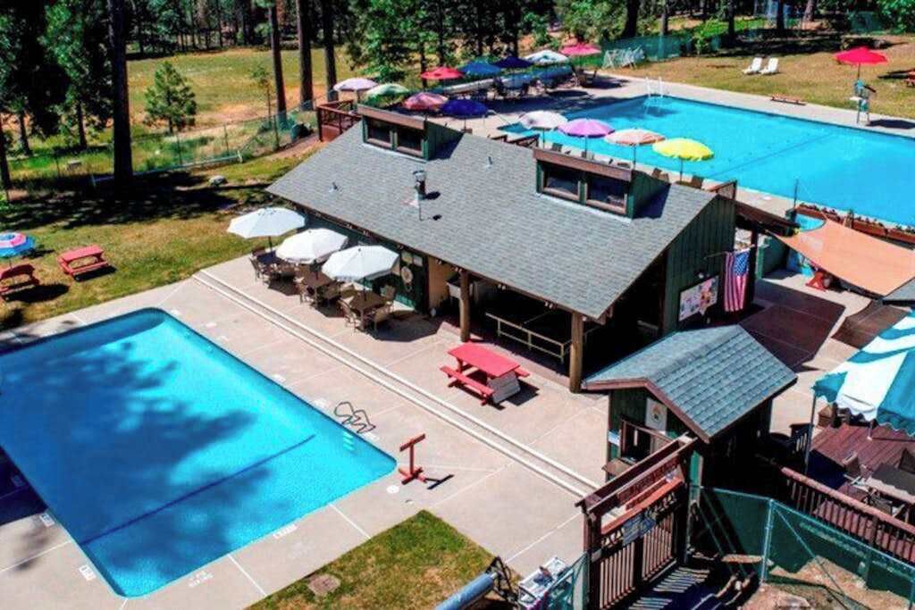 Ein Schwimmbeckenbereich mit Liegestühlen und Sonnenschirmen, ein überdachter Sitzbereich und eine Flagge.