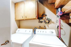 A laundry area with two white washing machines, wooden cabinets, and a decorative wreath. - Under The Trees - Big Trees Village (Camp Connell)