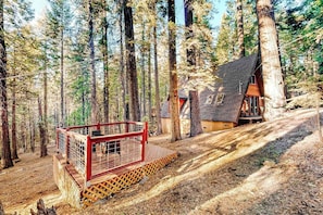 A cabin in a forest with a red deck and a dirt path leading to it. - Under The Trees - Big Trees Village (Camp Connell)