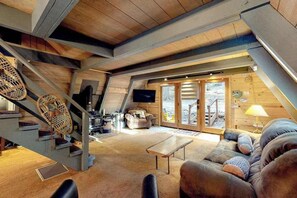 A loft-style room with a staircase, a sofa, a coffee table, and a television. - Under The Trees - Big Trees Village (Camp Connell)