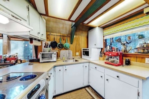 A compact kitchen with white cabinets, a stove, a microwave, and a red coffee machine. - Under The Trees - Big Trees Village (Camp Connell)