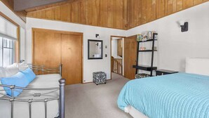 A bedroom with a bed, a bedside table, a wardrobe, and a mirror. - Bigfoot Cabin - Big Trees Village (Camp Connell)
