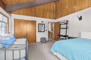 A bedroom with a bed, a bedside table, a wardrobe, and a mirror. - Bigfoot Cabin - Big Trees Village (Camp Connell)