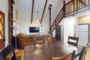 Ein großzügiger Wohnbereich mit Esstisch aus Holz, Sofas und einer Treppe.