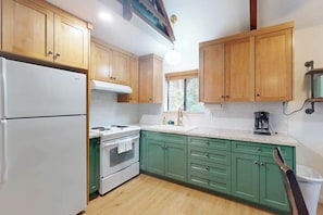 A kitchen with wooden cabinets, a white refrigerator, a stove, and a sink. - Deaver's Cabin - Dogwood Mountain (Shaver Lake)