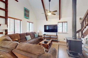 A living room with a sofa, television, and a wood-burning stove. - Deaver's Cabin - Dogwood Mountain (Shaver Lake)