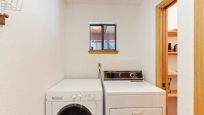 A laundry room with a washing machine and dryer, a small window, and a wooden door leading to a closet. - Hot Tub Hideaway - Big Trees Village (Dorrington)