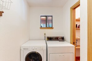 A laundry room with a washing machine and dryer, a small window, and a wooden door leading to a closet. - Hot Tub Hideaway - Big Trees Village (Dorrington)