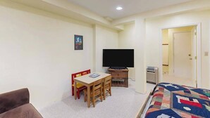 A room with a bed, a television, a desk with chairs, and a door leading to another room. - Hot Tub Hideaway - Big Trees Village (Dorrington)