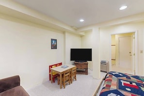 A room with a bed, a television, a desk with chairs, and a door leading to another room. - Hot Tub Hideaway - Big Trees Village (Dorrington)
