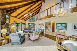 A spacious living room with a high ceiling, a staircase, and a chandelier. - Rustic Lakefront Retreat - Pine Mountain Lake (Groveland)