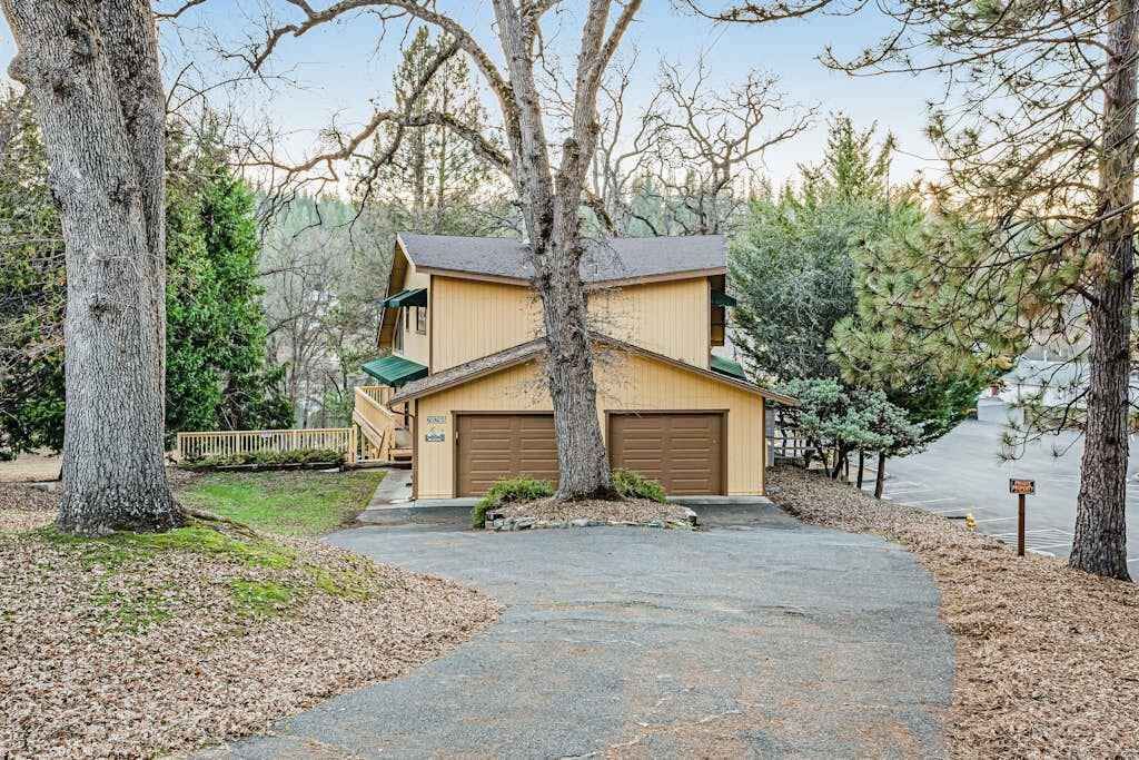 A two-story building with a garage, surrounded by trees and a clear sky.