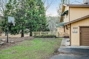 A two-story building with a basketball hoop, a wooden deck, and a garage door with a welcome sign. - Rustic Lakefront Retreat - Pine Mountain Lake (Groveland)
