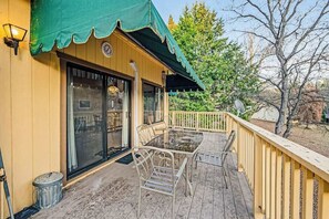 A covered outdoor deck with a table and chairs, a trash can, and a lamp post. - Rustic Lakefront Retreat - Pine Mountain Lake (Groveland)