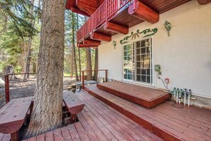 A wooden deck with benches, a covered area with a red railing, and a building with a green sign.