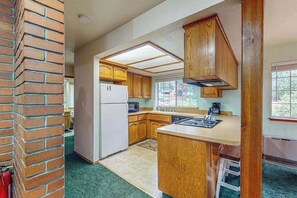 Cocina con armarios de madera, refrigerador, microondas y ventana que proporciona luz natural.