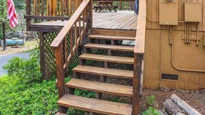 A wooden staircase leading to a deck area with a picnic table and a utility box. - The Dollhouse Cabin - Blue Lake Springs (Arnold)