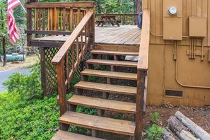 A wooden staircase leading to a deck area with a picnic table and a utility box. - The Dollhouse Cabin - Blue Lake Springs (Arnold)