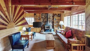 A cozy cabin interior with a stone fireplace, wooden furniture, and a television. - The Dollhouse Cabin - Blue Lake Springs (Arnold)