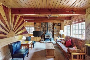 A cozy cabin interior with a stone fireplace, wooden furniture, and a television. - The Dollhouse Cabin - Blue Lake Springs (Arnold)