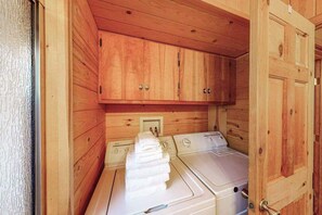 A laundry room with wooden cabinets and two washing machines. - The Dollhouse Cabin - Blue Lake Springs (Arnold)
