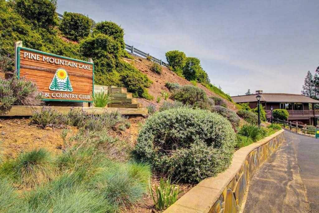 A sign for Pine Mountain Lake Country Club with a landscaped area and a building in the background.