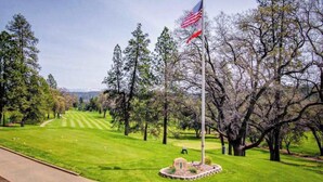A golf course with a flagpole, trees, and a clear sky. - High Score Hideaway - Pine Mountain Lake (Groveland)
