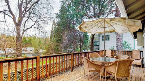 A wooden deck with wicker furniture and a glass table, overlooking a wooded area. - High Score Hideaway - Pine Mountain Lake (Groveland)