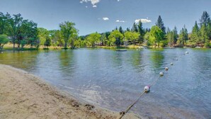 A lakeside view with clear water, a sandy beach, and trees in the background. - High Score Hideaway - Pine Mountain Lake (Groveland)