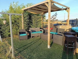 An outdoor patio area with wicker furniture and a pergola structure.