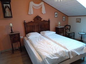A bedroom with a wooden bed, two bedside tables with lamps, a chair, and a small table with a lamp.