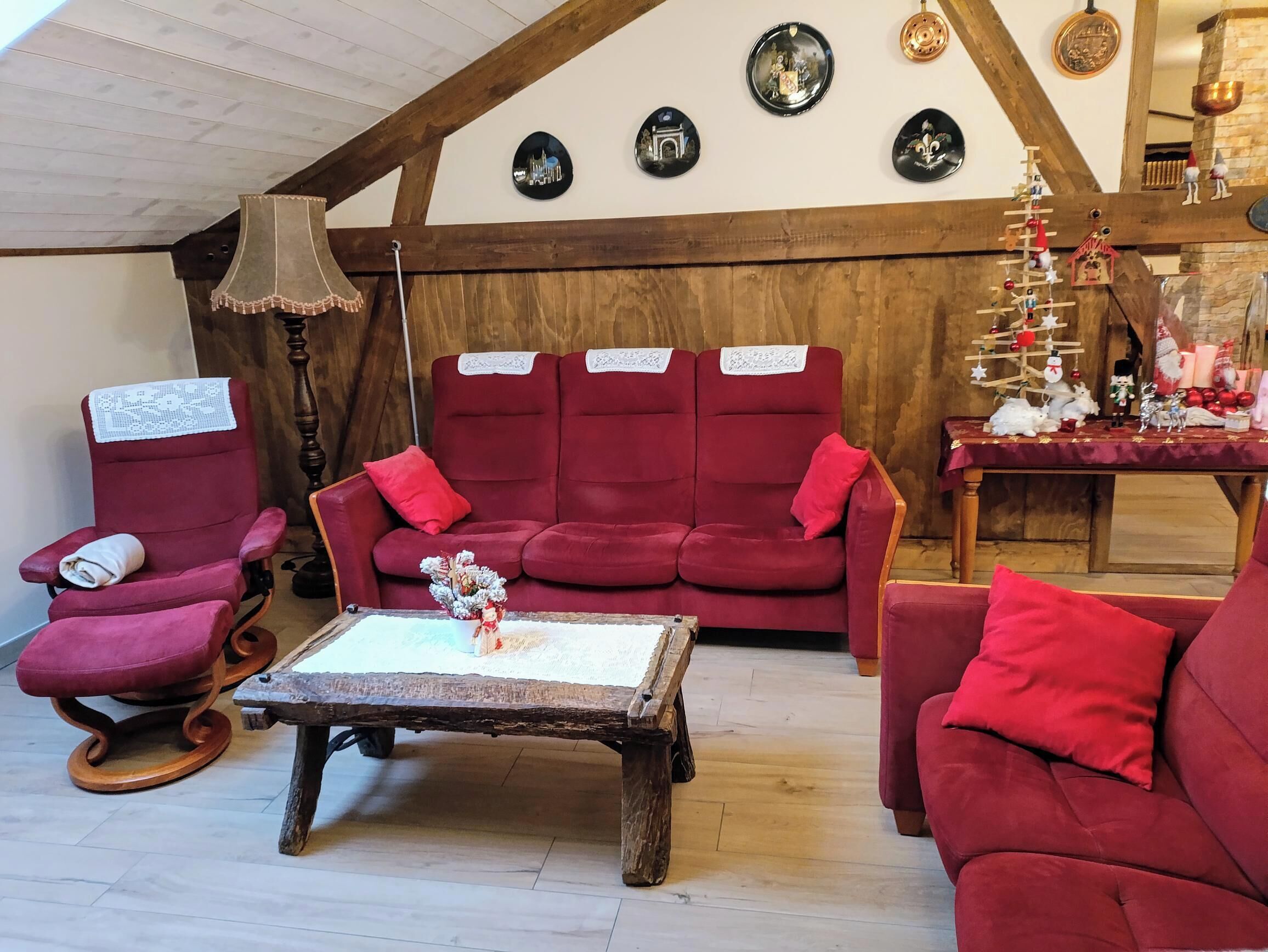 Ein gemütliches Wohnzimmer mit einem roten Sofagarnitur, einem Holztisch und einer Lampe.