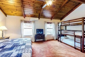 Ein Schlafzimmer mit Etagenbett, Fernseher auf einer Kommode und Deckenventilator.