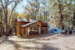 A cabin with a large glass front, surrounded by trees. - Creekside Cabin - Pine Mountain Lake (Groveland)