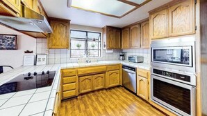 A kitchen with wooden cabinets, a microwave, an oven, and a dishwasher. - Creekside Cabin - Pine Mountain Lake (Groveland)