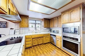Eine Küche mit Holzausstattung, einer Mikrowelle, einem Backofen und einem Geschirrspüler.