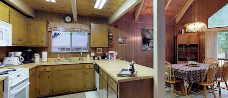 A kitchen with wooden cabinets, a central island, and a dining area with a table and chairs.