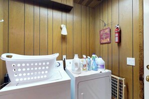 Een wasruimte met een wasmachine, een droogrek en verschillende schoonmaakmiddelen.