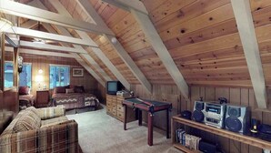 Een knus zolderkamertje met een hoogslaper, een kleine televisie, een pooltafel en een verzameling speakers.