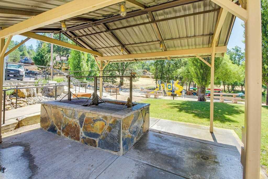 Un espacio al aire libre con techo, que cuenta con una chimenea de piedra, asientos y vistas al parque circundante.