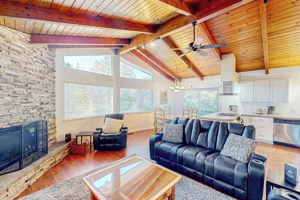 A spacious living area with a fireplace, leather sofa, and a dining table.