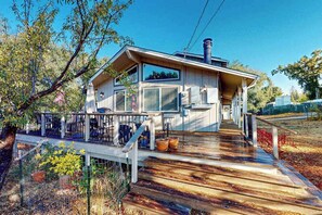 A modern house with a wooden deck, large windows, and a chimney.