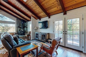 A spacious living room with a fireplace, leather sofa, wooden coffee table, and a television mounted on the wall. - Pine Mountain Magic - Pine Mountain Lake (Groveland)