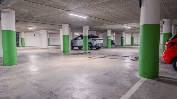 A parking garage with concrete pillars, a white car, and a red car parked. - 103 Relais du Lac Village - Italian Homing (Desenzano del Garda)